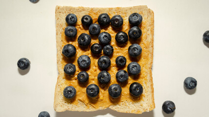 Toast with peanut butter and blueberries on a white plate. View from above