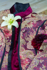 dunkelrote jacke aus samt und seide mit blumendekor bestehend aus einer weißen lilienblüte und einer roten dahlienblüte