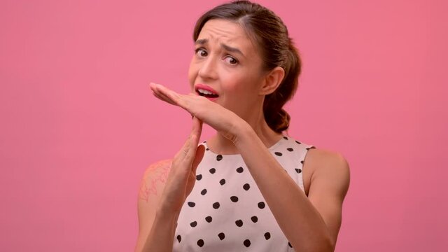 Studio shot of sad dissatisfied tired frustrated woman shows timeout gesture, needs stop, asks time for rest after hard work, demonstrates break hand sign, over pink background. Body language concept