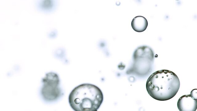Macro shot of various air bubbles in water rising up on light blue background. Super slow motion filmed on high speed cinema camera at 1000 fps.