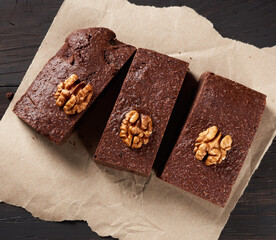 baked pieces of brownie chocolate cake with nuts on a brown piece of paper