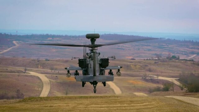 A AH-64 Apache helicopter hovering over ground