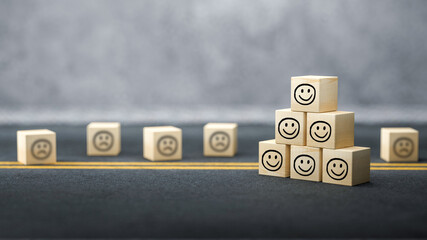 cubes with happy emoticons as a group and unhappy ones in the back on concrete background