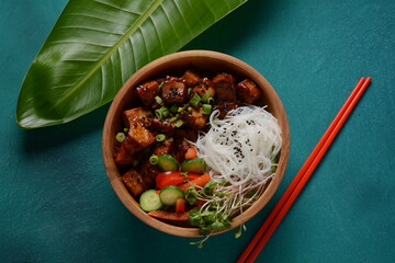 Fried tofu with rice crystal noodles in a wooden bowl.