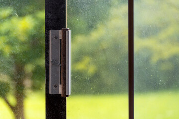 Dusty window glass, slide door handle, against sunny day outdoor in background