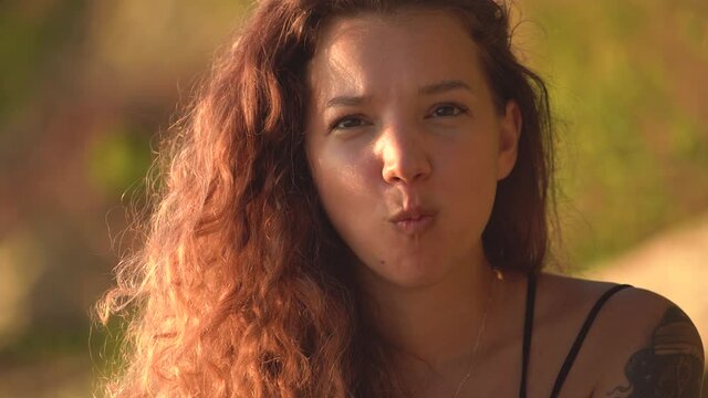 Portrait of cheerful young woman making duck face funny cute facial expression. Brunette woman with chubbby face, making cute baby face.