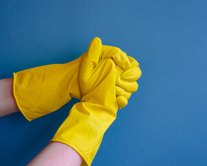 yellow household gloves for cleaning on a blue background. handshake, support symbol