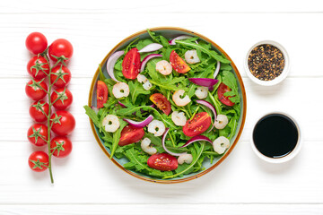 Mediterranean diet menu concept Healthy salad of fresh vegetables - tomatoes, arugula, purple onions, shrimps, soy sauce and sesame seeds in plate on white wooden table Vegan food Flat lay Top view