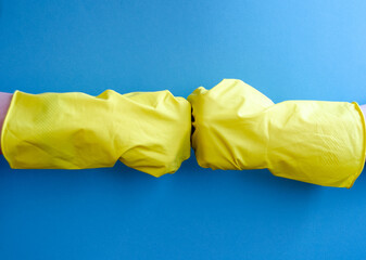 yellow household gloves for cleaning on a blue background. hello, good luck sign