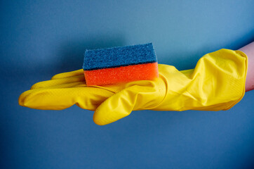 yellow household gloves for cleaning on a blue background, sponge