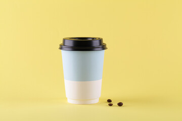 take away paper cup for coffee with coffee beans on yellow background