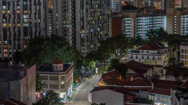 Aerial view of intersection and art deco shophouses with red roofs along Neil road in Chinatown area night timelapse. Traffic on the street with crossroad and crossing