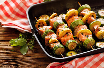 Salmon skewers with zucchini in herbal marinade in a grill pan close up view