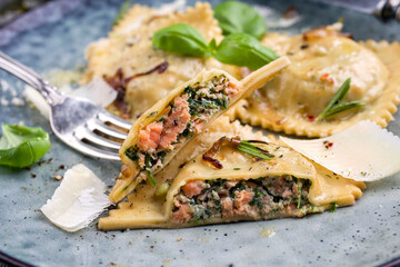 Traditional Italian salmon spinach ravioli offered as close-up on a design plate