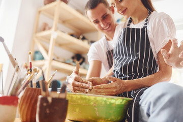 With her boyfriend or husband. Young female ceramist have a works indoors with handmade clay product. Conception of pottery