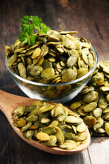 Composition with bowl of pumpkin seeds on wooden table