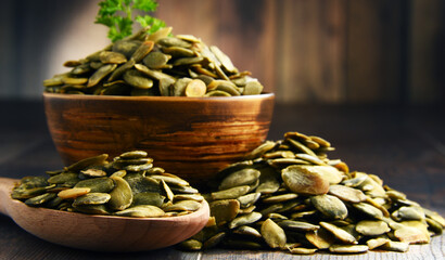 Composition with bowl of pumpkin seeds on wooden table