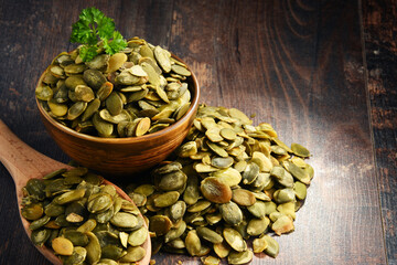 Composition with bowl of pumpkin seeds on wooden table