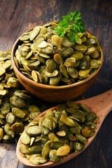 Composition with bowl of pumpkin seeds on wooden table