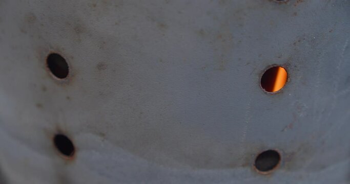 Close up shot of barbecue charcoal chimney starter with flame peeking through ventilation hole
