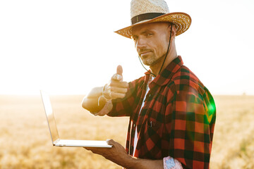 Image of adult man working with laptop while pointing finger at camera