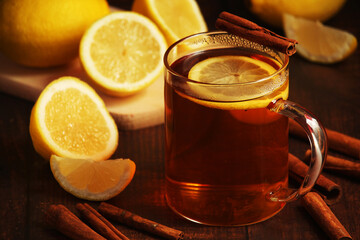 A mug with hot tea with lemons and cinnamon sticks	
