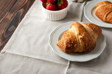 Fresh golden croissants with strawberries on napkin. Breakfast time. Top view