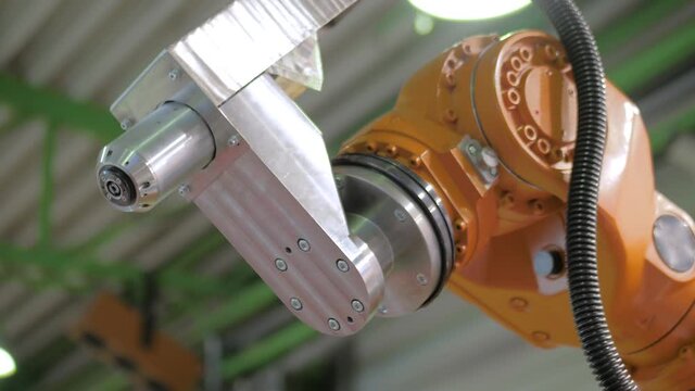 Orange industrial robotic arm manipulator moves and demonstrates working process at robot exhibition, trade show - close up view. Manufacturing, engineering, futuristic, ai, technology concept