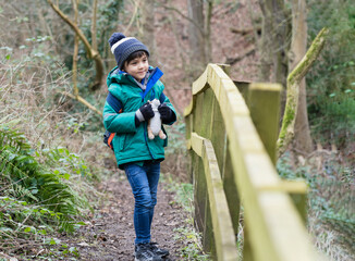 Naklejka na ściany i meble Full length Portrait of healthy boy looking at camera with smiling face, Child explorer and learning about wild nature in countryside, Kid carrying backpack adventure in forest with school trip