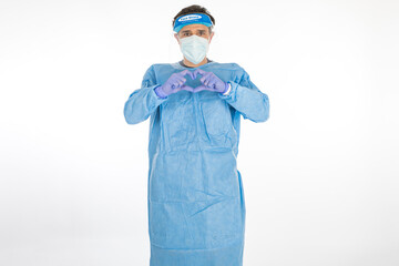 Doctor wearing blue PPE to fight coronavirus, forming a heart with his hands, on white background. Warrior. COVID medicine concept