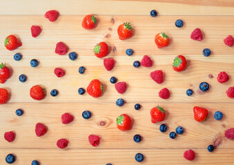 Naklejka na ściany i meble Strawberries, blueberries and raspberries on wooden background