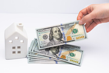 White house with cash dollar banknotes in hands, as a symbol of bank credit taken as a loan.