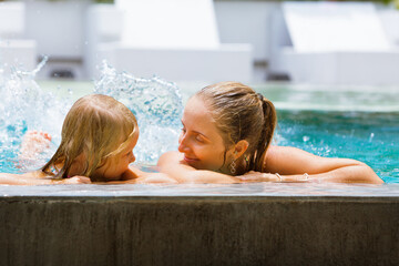 Happy people have fun at pool side edge. Funny photo of young mother with child relaxing in outdoor...