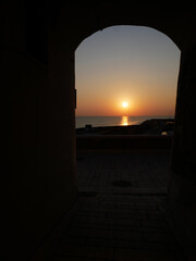 Termoli: In the foreground the silohuette of an arch of the old village, in the background the sun rising from the sea