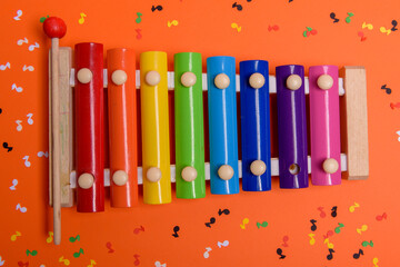 Wooden xylophone in rainbow colors for children an isolated on orange. Paper colorful musical notes...