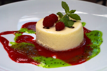 Cheesecake with fresh raspberries. Cottage cheese dessert with raspberry jam and kiwi on a white plate.