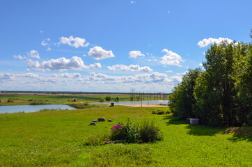 Old wooden house, green field, trees, flowers and grass, and blue sky