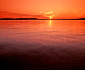 Obraz premium Sun setting over calm smooth Lake Superior in the upper Peninsula of Michigan in the United States