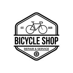 Obraz premium bike shop logo badge and label. Old style bike shop and repair type logo vector