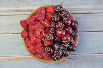 top view of fresh cherry and raspberries in rustic bowl © cesar