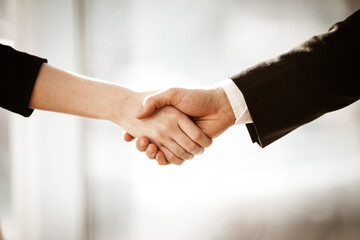 Successful business concept. Young businesswoman and businessman shake hands closeup after signing partnership cooperation contract in office. Two managers man and woman teamwork indoors.