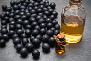 Grapes and grape essential oil juice on the gray table background with copy space.