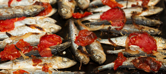 Baltic herring baked in a baking tray with tomatoes and onions.