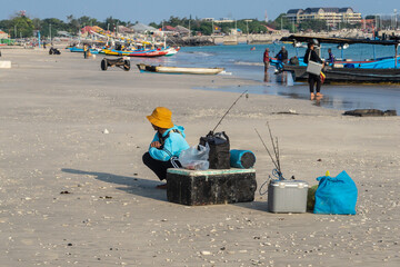 Fisherman on the beach with box and fishing rods