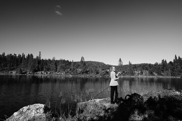 A young girl fishes in a small lake in the wild nature of Norway, Hallingdal, Gol. Shot in black...