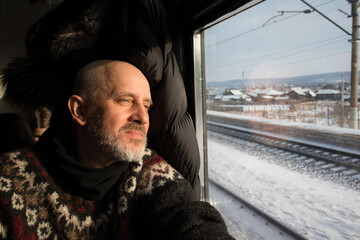 Mann sitzt im Zug und schaut aus dem Fenster auf die  russische Winterlandschaft