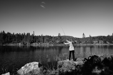 A young girl fishes in a small lake in the wild nature of Norway, Hallingdal, Gol. Shot in black...