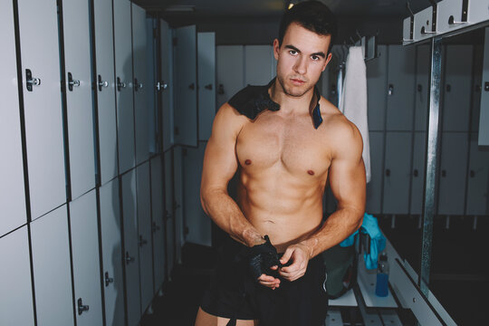 Attractive Professional Athlete Removing Weight Lifting Gloves Standing In Gym's Locker Room