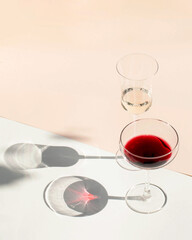 A glass of wine in the harsh light with nice long shadows on a light background. Trending photos, minimalism. Copy space