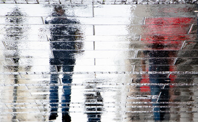 Blurry reflection shadow silhouette on wet street of people walking on a rainy day - 370784526
